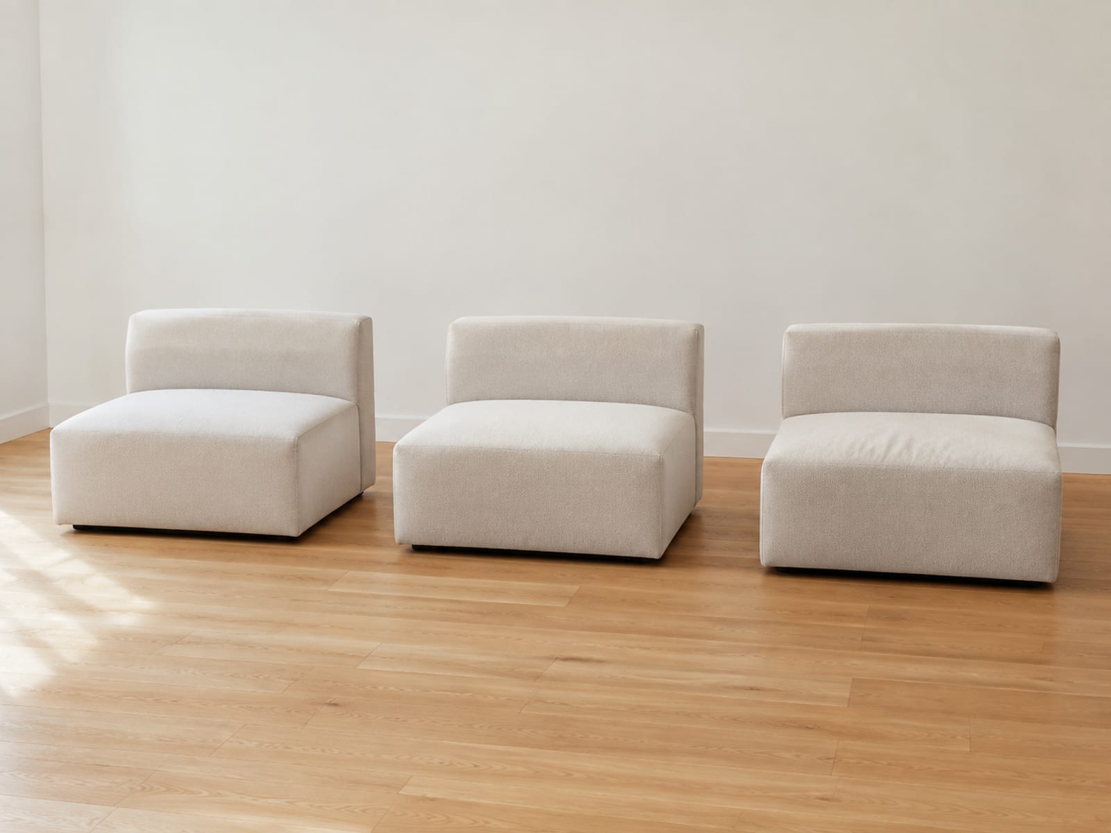 Three identical upholstered seat modules of one sectional standing separated in a line on bare floorboards with clear floor visible between each
