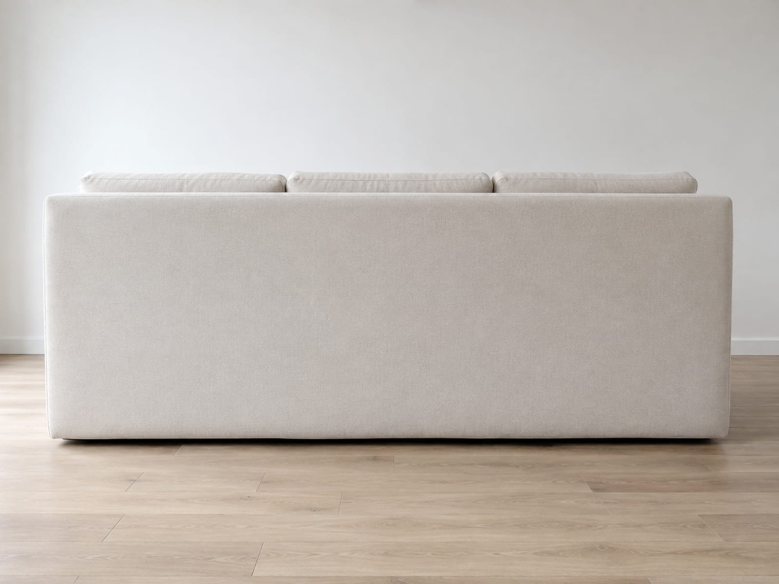 A three-seat sofa seen from directly behind, its plain outside back an unbroken expanse of upholstery with the tops of the back cushions just visible