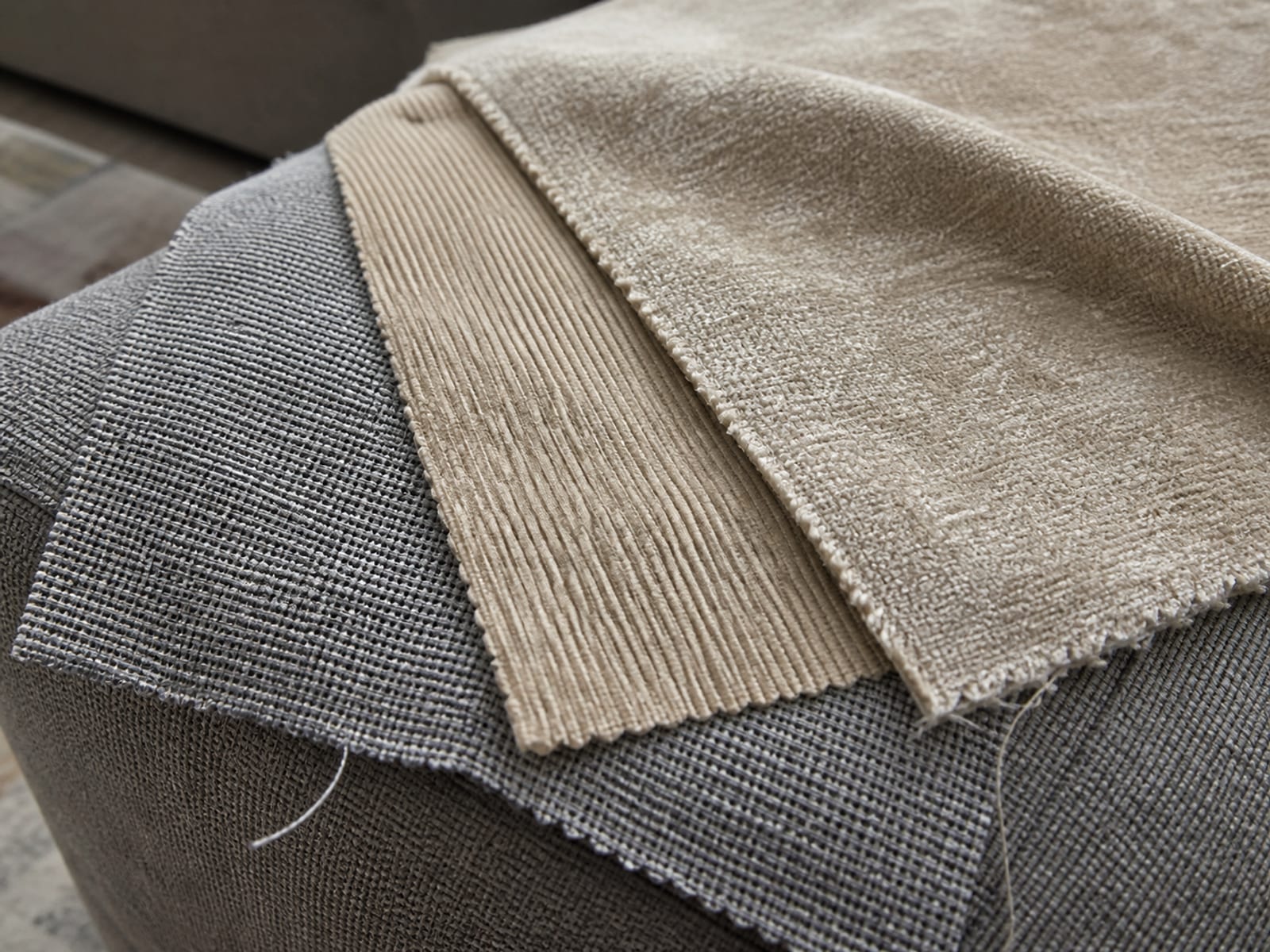 A tight flatweave, a corduroy and a brushed chenille swatch laid overlapping on a sofa arm