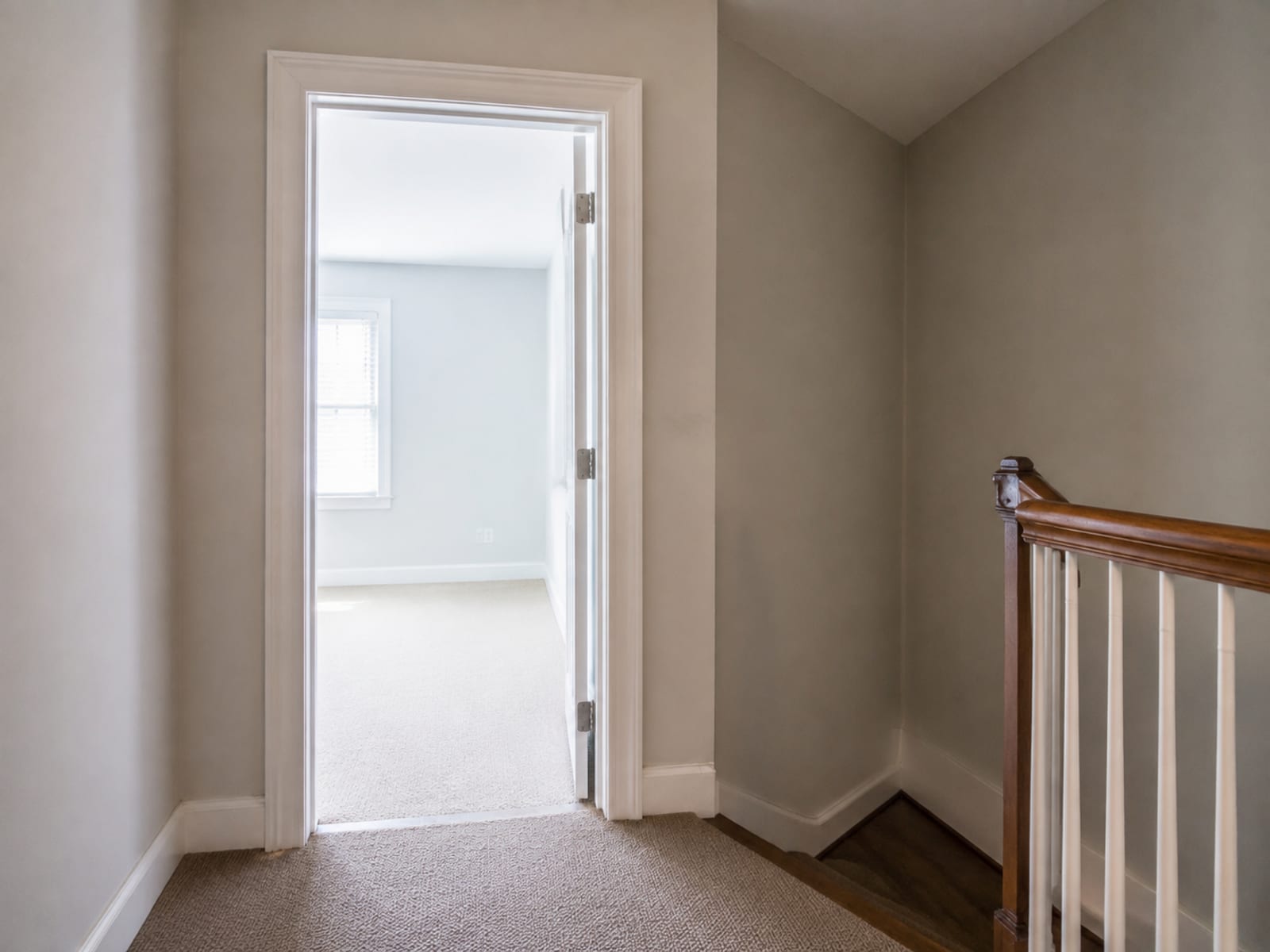 An open interior doorway at the top of a stair turn, empty, with the tight angle of the landing behind it