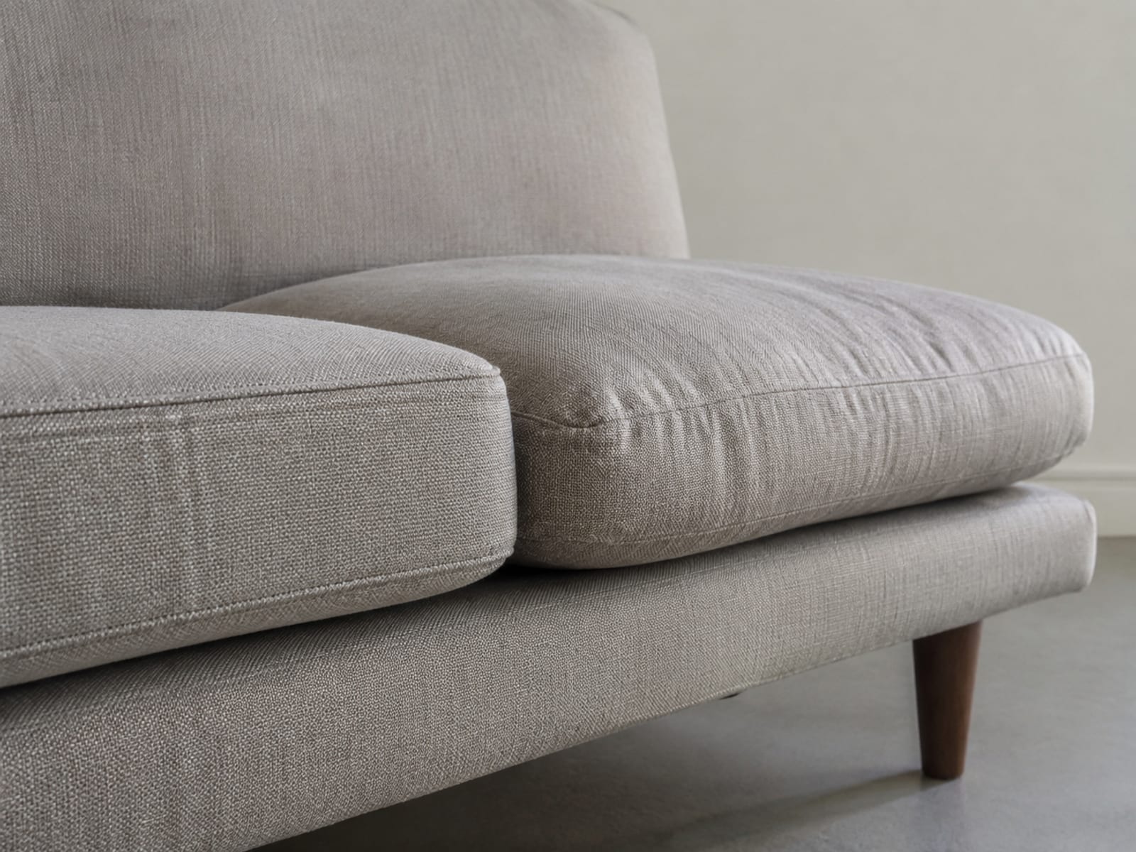 Two seat cushions on one sofa seen in profile, one shallow and firm, the other deep and sinking softly