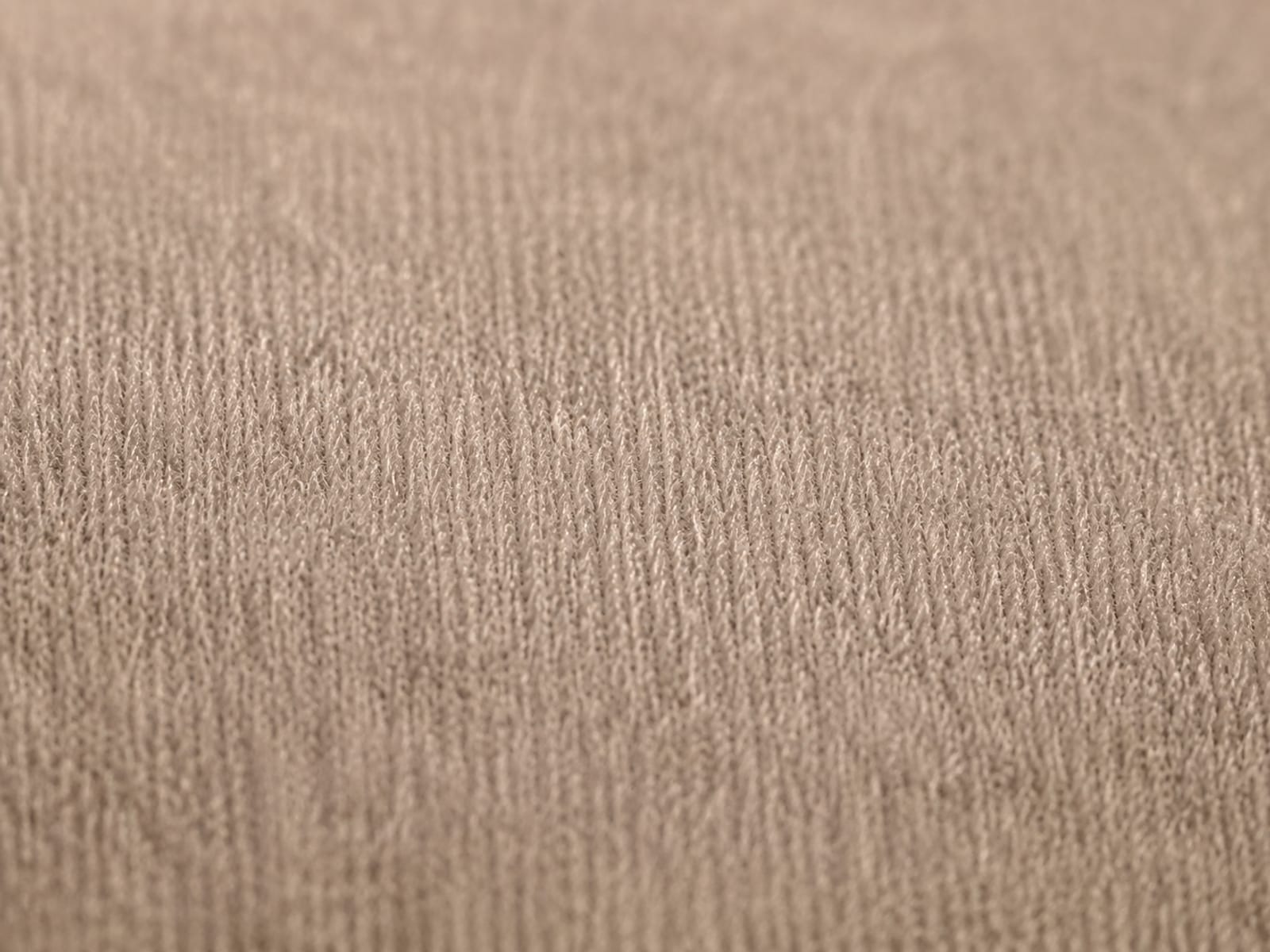 An extreme close view of pale microfiber pile filling the frame, the fibers standing evenly and catching a low raking light