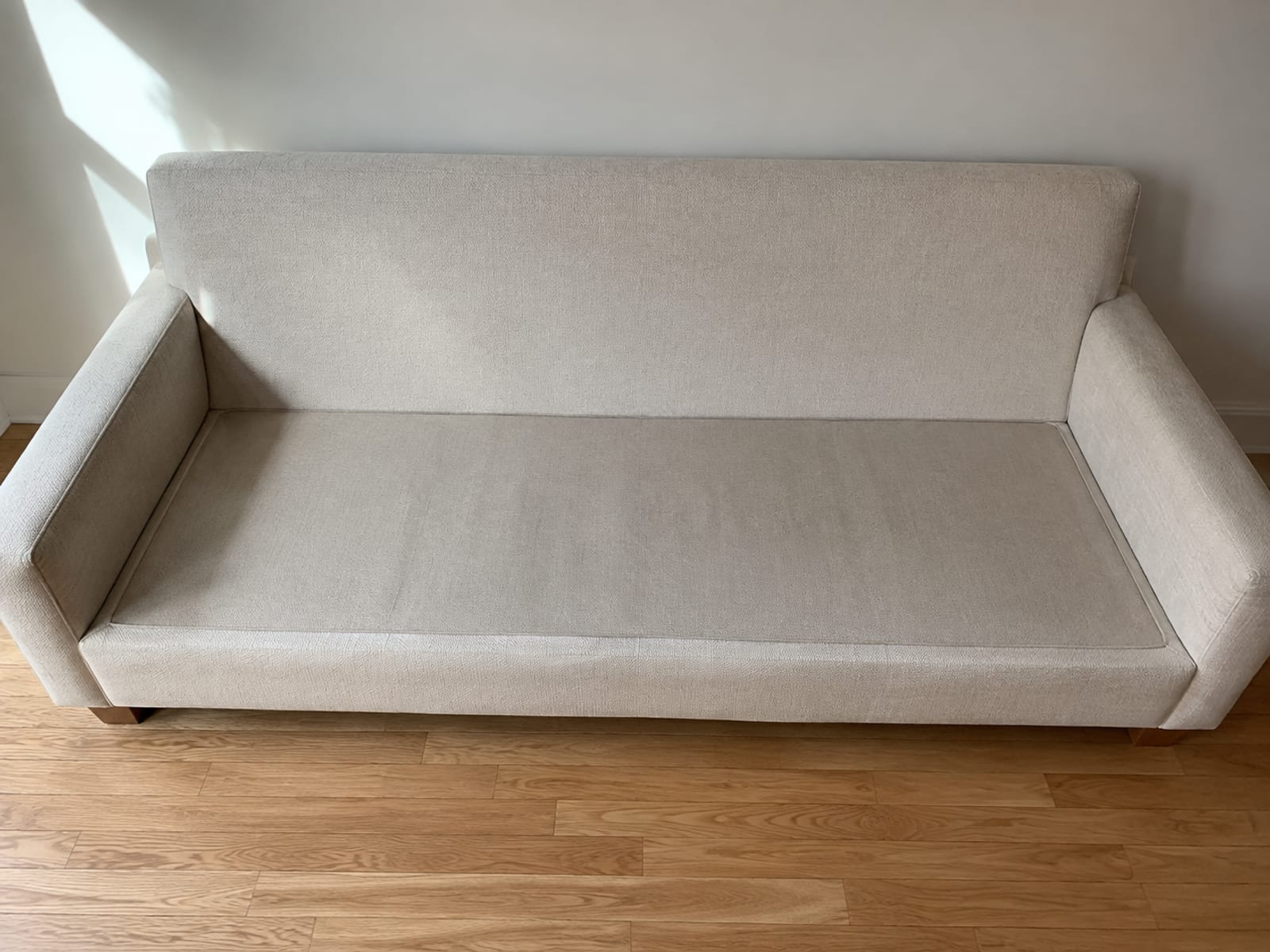 A three-seat sofa seen from slightly above with all seat cushions taken away, the flat upholstered deck platform open across the full width