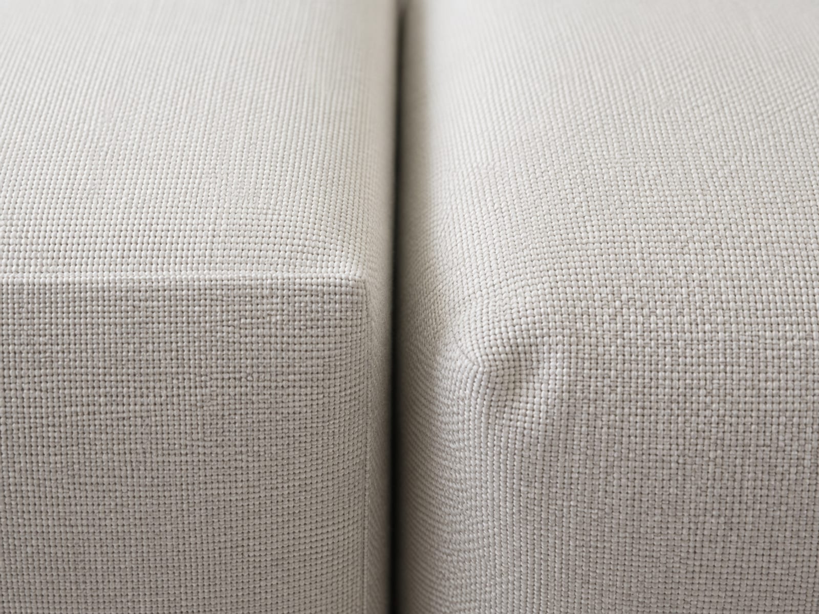 An extremely close view of two seat cushion corners meeting edge to edge, the left holding a crisp square edge and the right rounded and settling softly under its own weight