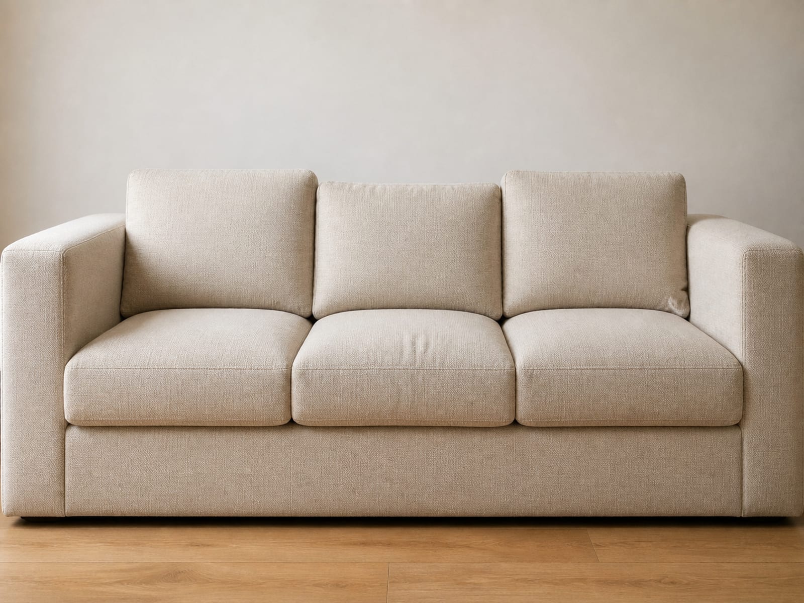 A three-seat sofa photographed square on, close enough that both arms and the seat between them fill the frame with the join seams visible