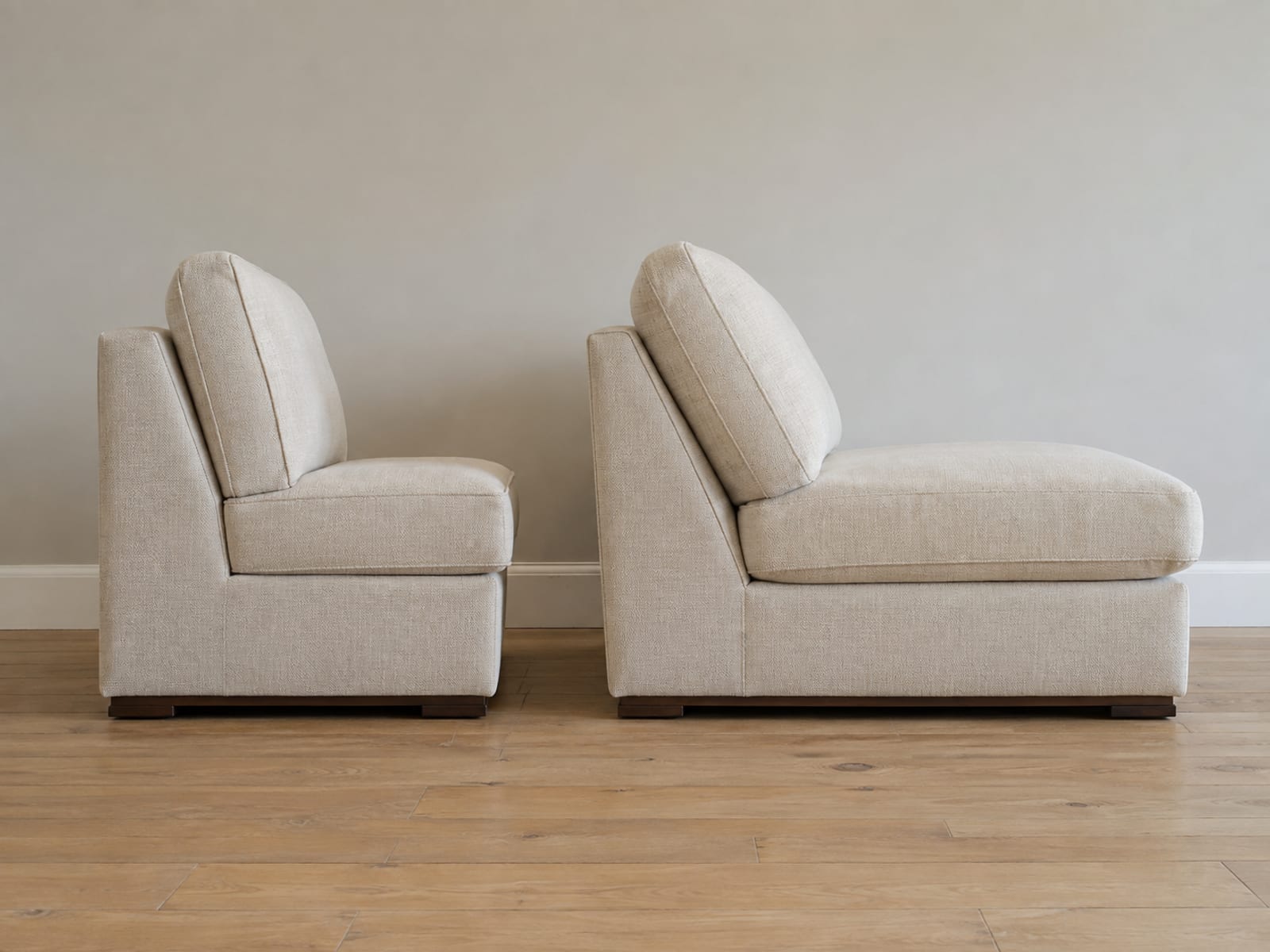 Two sofas side by side against the same wall photographed from the side at seat level, one with a shallow upright seat and one much deeper