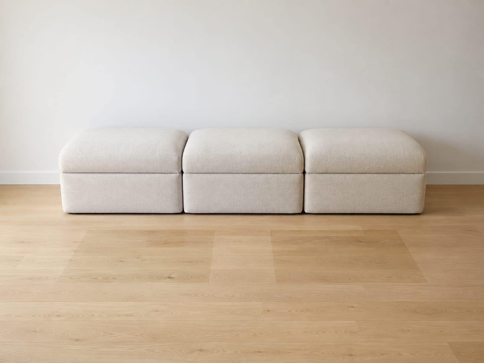 Three boneless seat modules in one fabric standing in a straight run against a wall, with two faint unfaded rectangles on the floorboards where two of them previously stood
