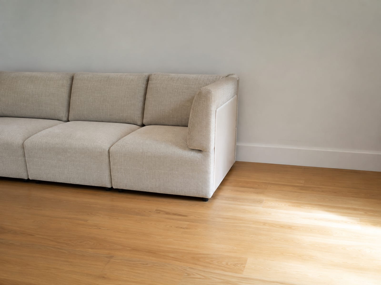 A three-seat modular run against a wall stopping short, with a bare rectangle of floor beside it exactly the width of one more module
