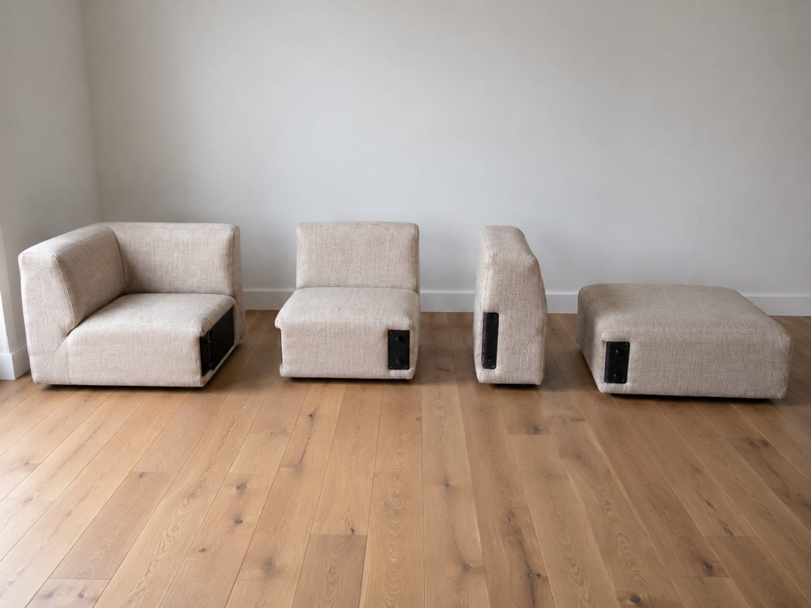 Four separate upholstered sections standing apart on bare boards, a corner unit, an armless seat, an arm piece and a low ottoman
