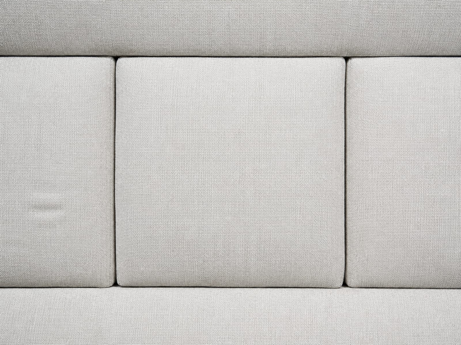A close view straight down onto the join where an ottoman meets the seat cushions on either side of it, the three surfaces sitting at the same height with only seam lines between them