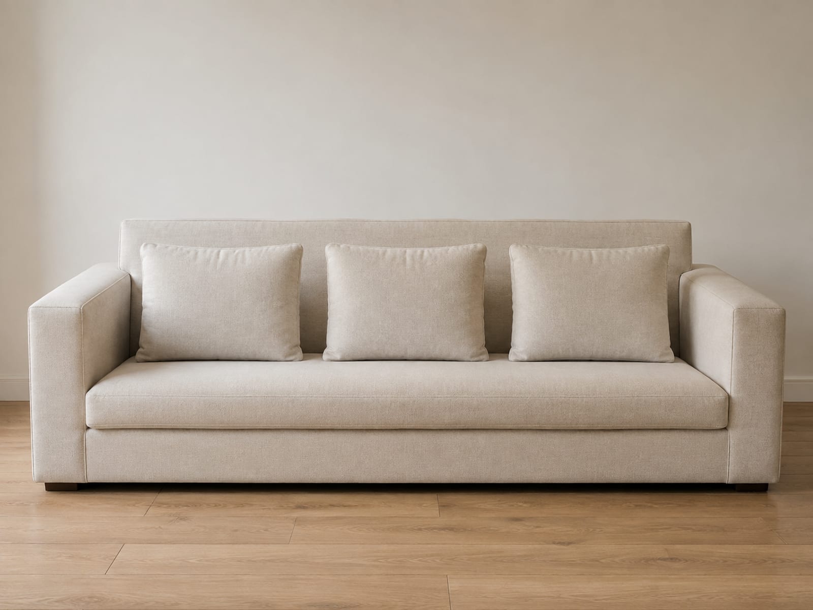 A sofa seen square from the front with its back cushions pulled forward and stood upright on the seat, exposing a strip of the bare back panel behind them