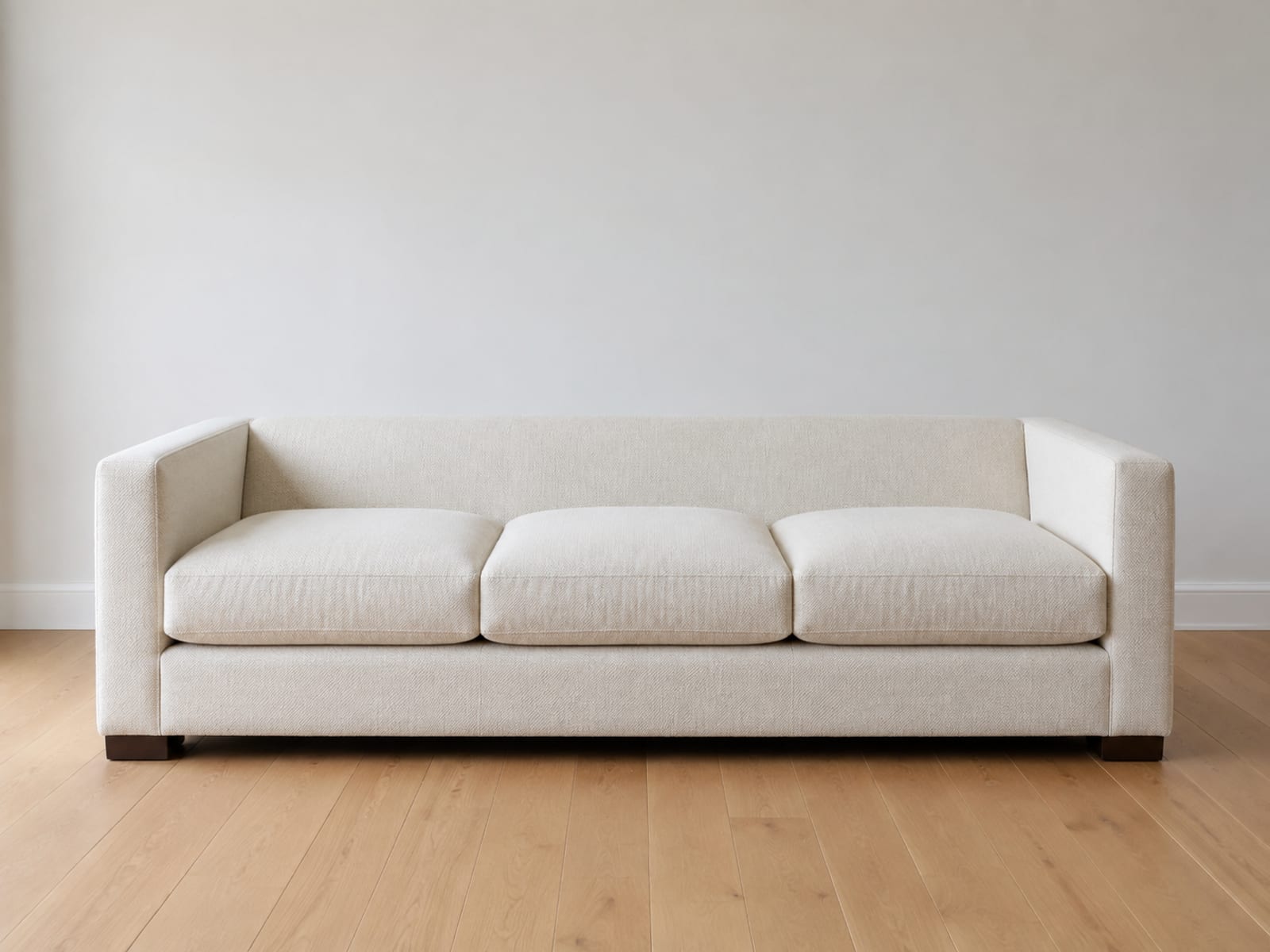 A sofa with every back cushion removed, seen square from the front so the plain upholstered back panel of the frame and its low height above the seat are fully exposed