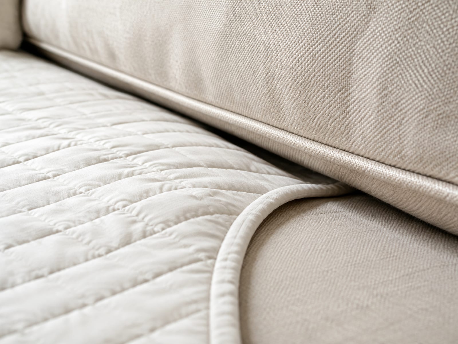A protector's fabric anchor tail pushed down into the crevice between a seat cushion and the sofa back