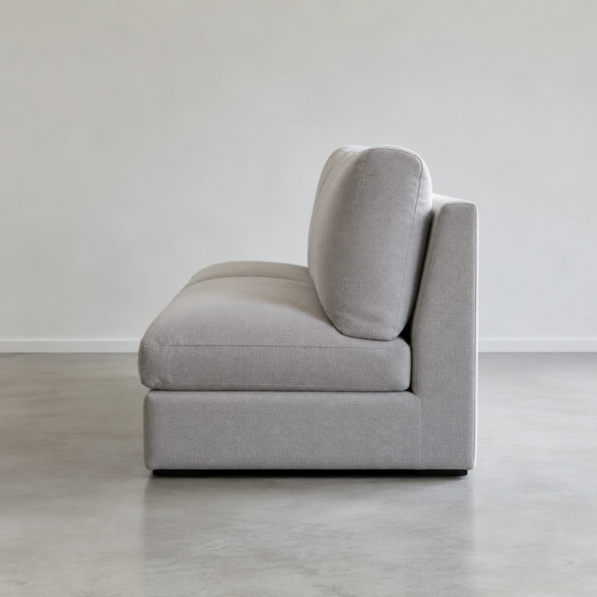 A deep upholstered sofa seen square from the side at seat level, the front-to-back run dividing into three zones: the long seat cushion, the thick back cushion, and the outside back panel