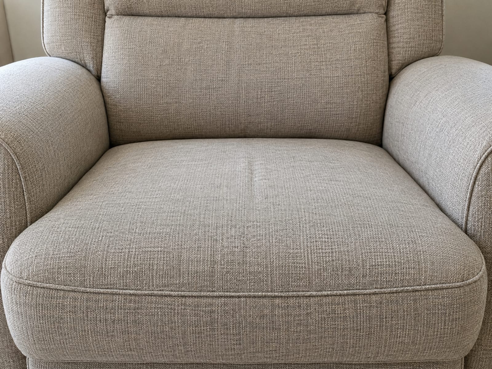 The seat of an upholstered lift chair in its ordinary upright position, photographed square on from the front at seat height and framed so the two padded arms stand at the left and right edges of the picture and the seat cushion between them fills the middle