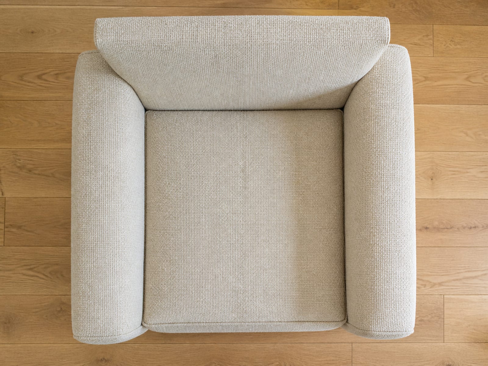 An upholstered armchair seen square from directly overhead so the seat cushion, both arms and the top edge of the back lie flat in the frame