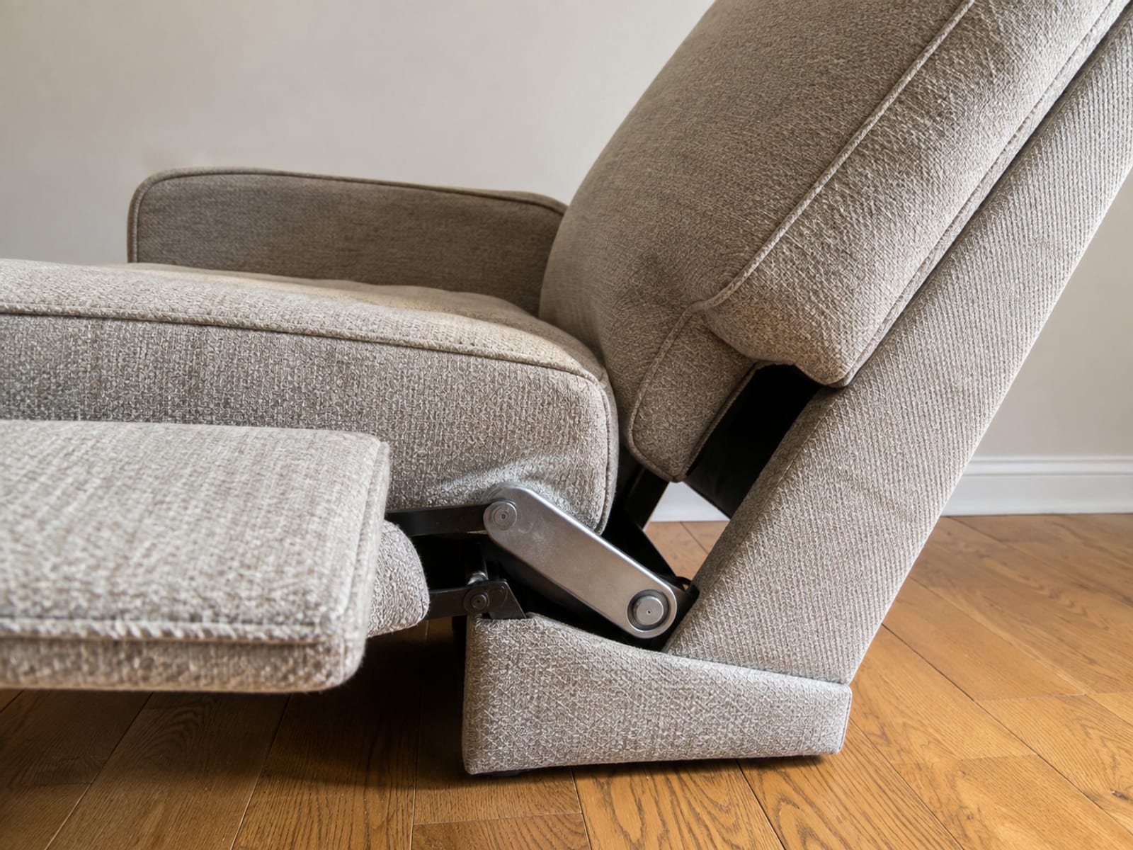 A close side view of a recliner part way through reclining, showing the gap where the seat meets the tilted back and the steel mechanism below