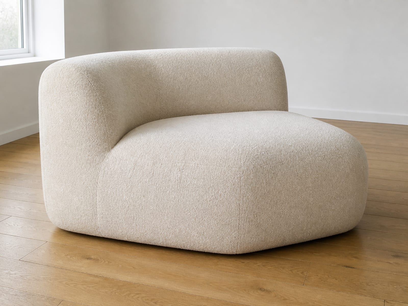 A single large boneless sofa seat unit standing alone on floorboards, its arm and back molded as one continuous soft form with no visible frame or legs
