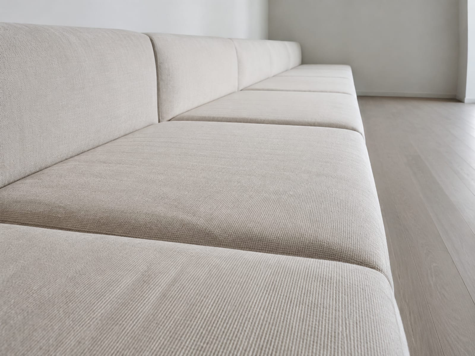 A low view down the length of a very long sectional from one end, the seat cushions receding one behind another with the joins stepping away