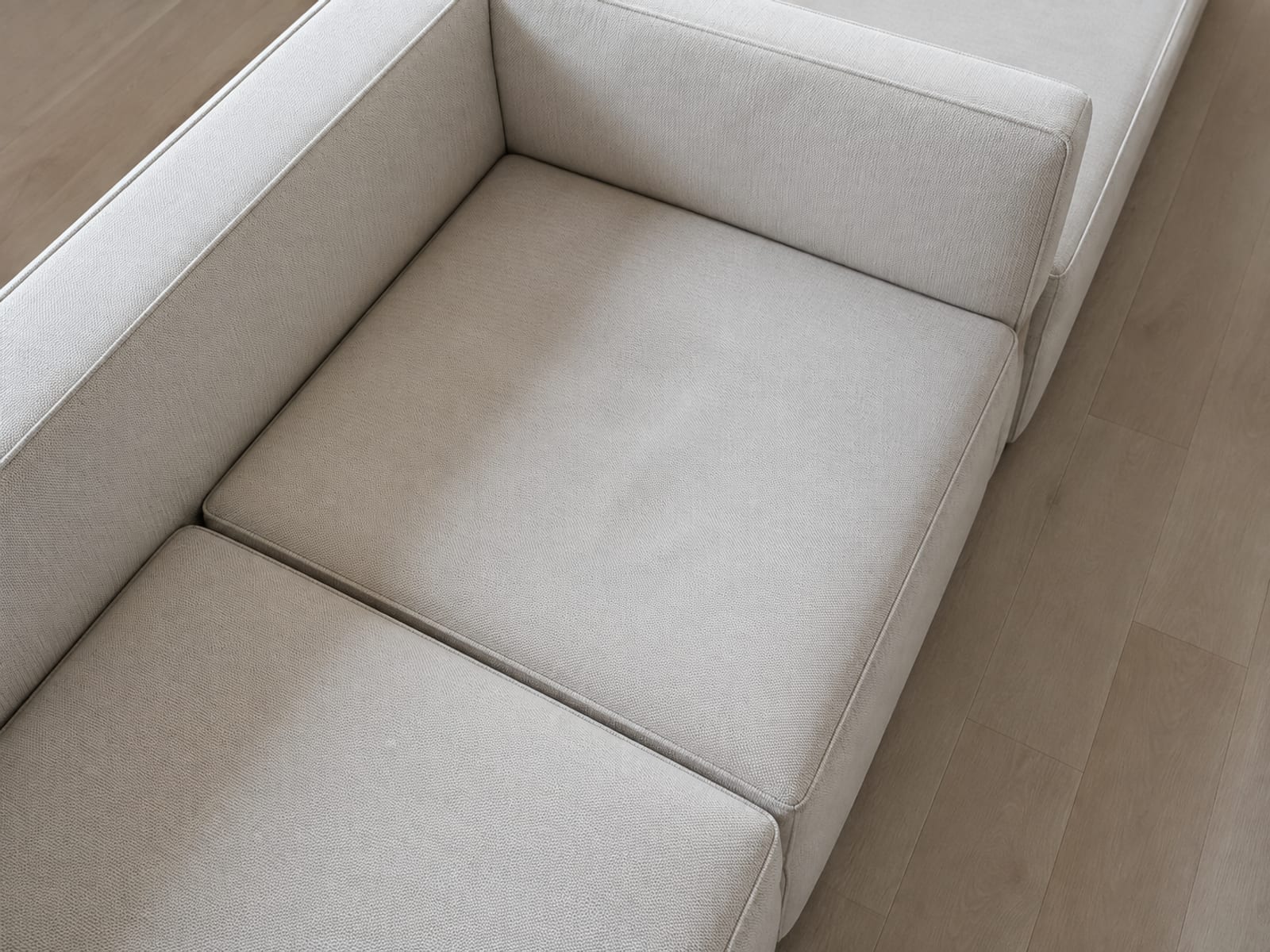 A view down onto the inside corner of an L-shaped sectional, the square corner seat cushion in the middle with one run leading left and the other away from the camera