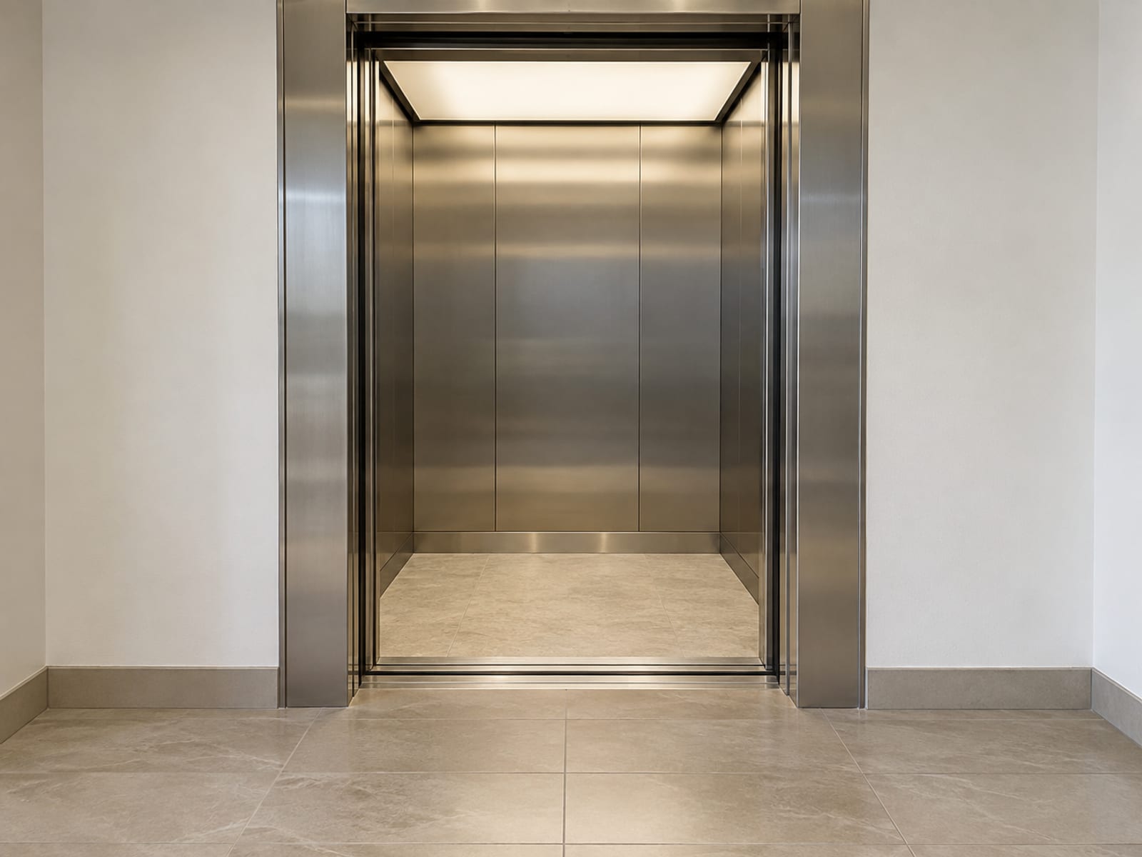 The open doors of an ordinary residential elevator car seen square on from the corridor outside at standing height, the car empty and evenly lit with plain brushed steel doors and plain walls