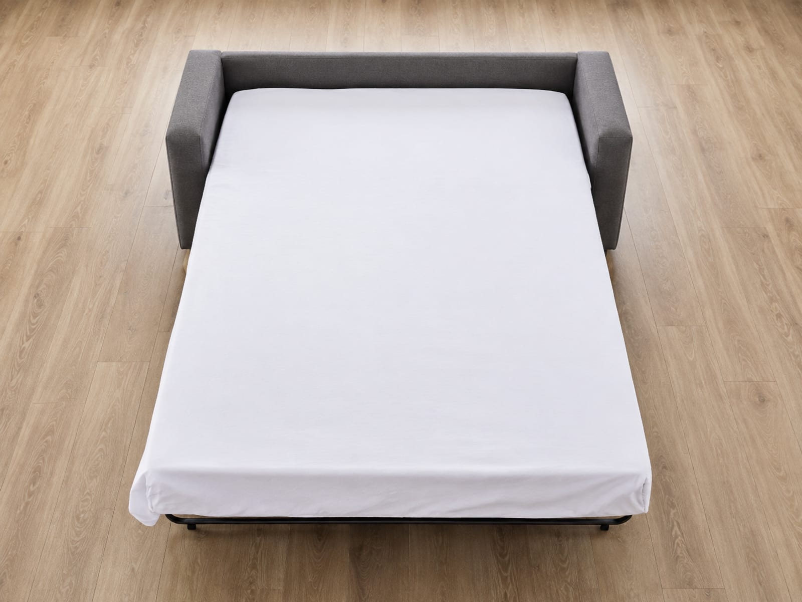 An opened sleeper photographed from above at the foot end so the whole rectangle of the sleeping surface reads against the floor
