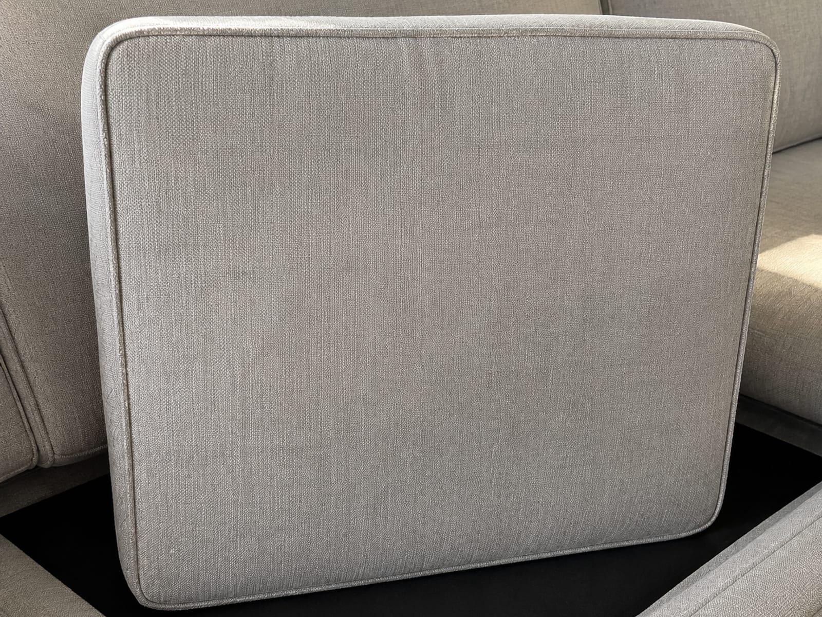 A sofa seat cushion tipped up on its front edge showing its plain unmarked underside