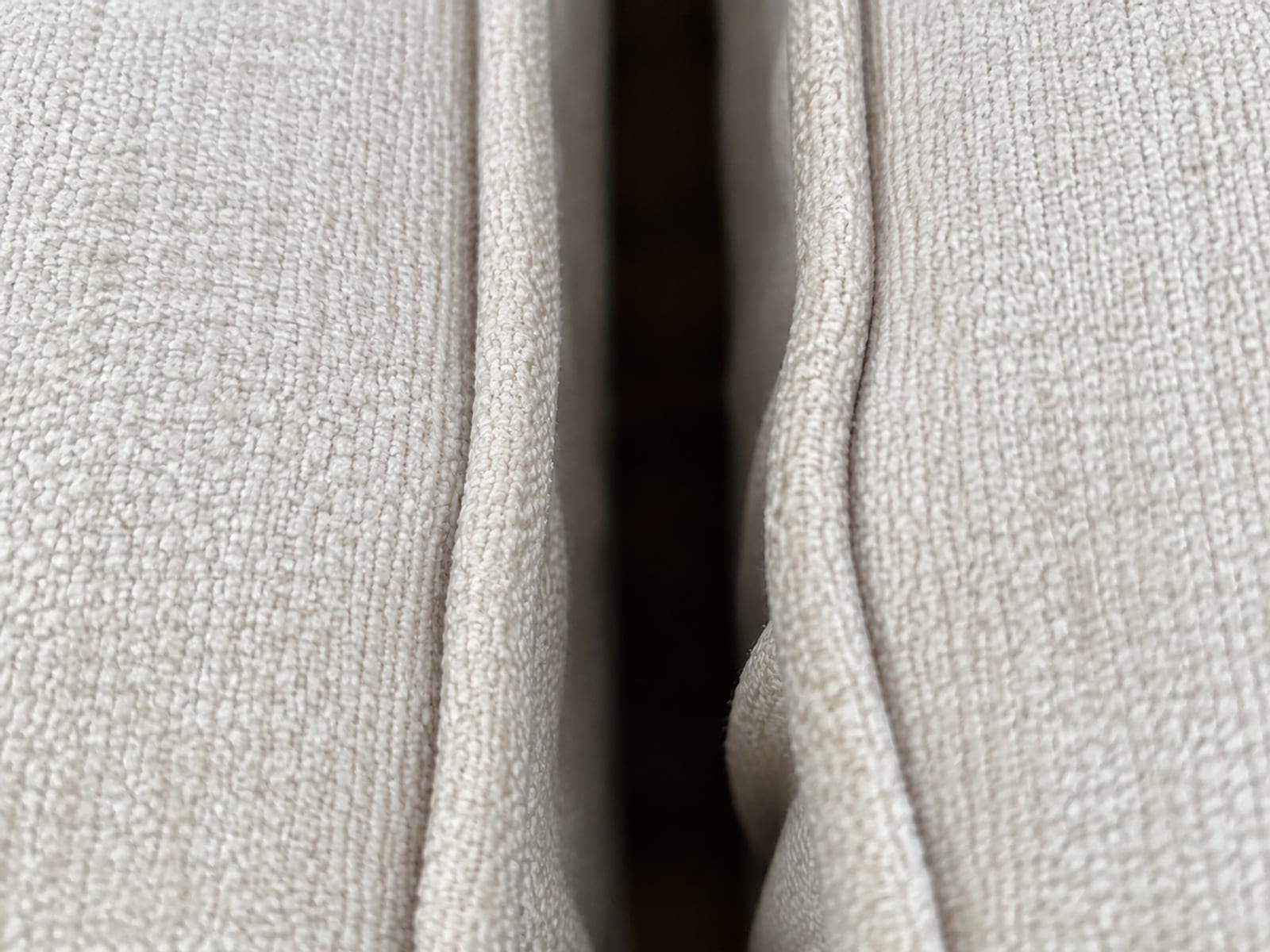 A close view down into the narrow gap where two separately covered seat cushions meet, a dark shadowed channel running down between the two fitted edges